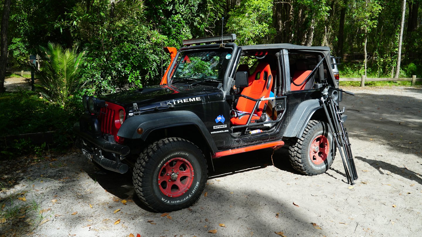 Black Jeep Wrangler modified for off-roading on dirt path.