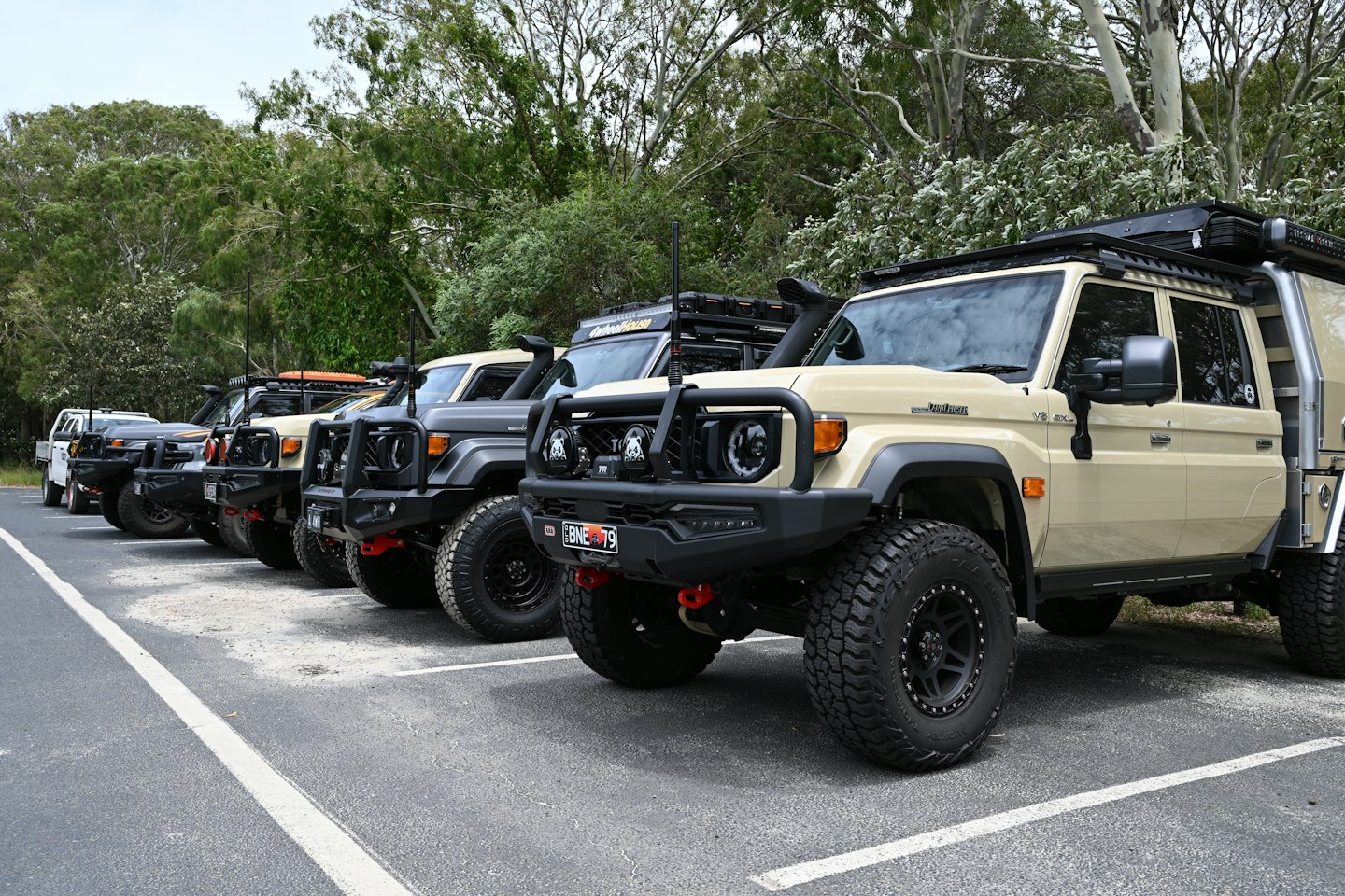 Five rugged, modified 4x4 vehicles parked in an asphalt lot.